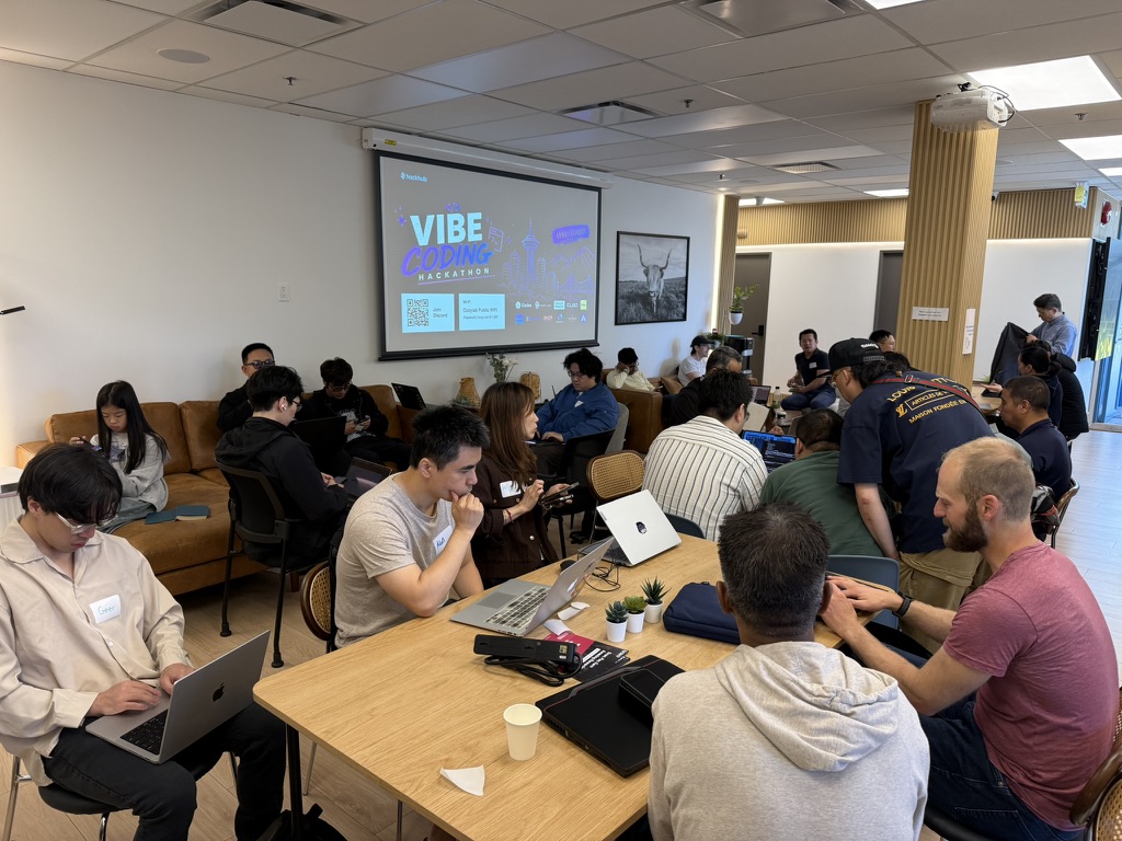 The venue at CozyLab Vancouver — everyone coding with the Vibe Coding Hackathon slide on screen
